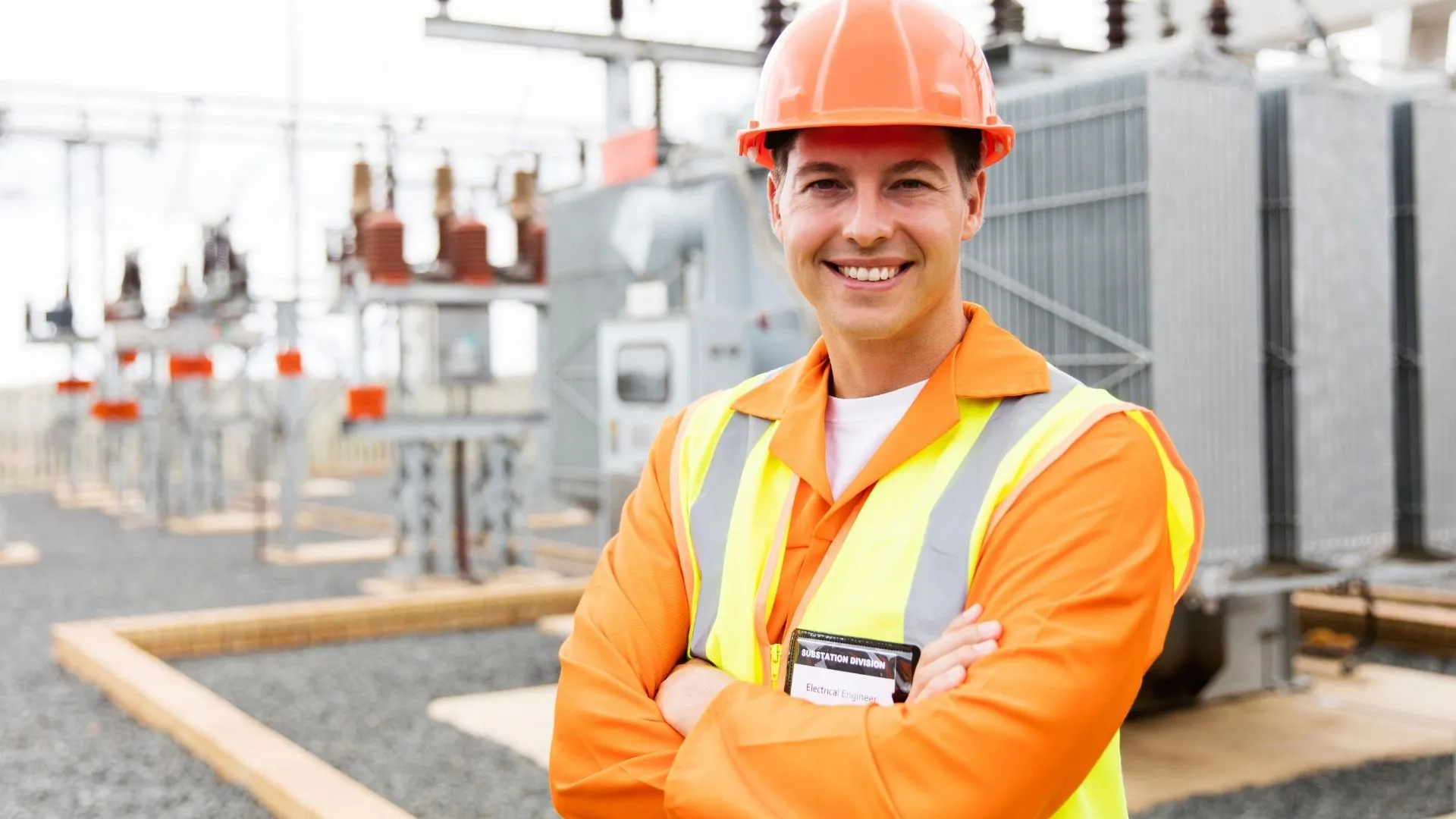 Ein Servicetechniker steht lächelnd vor einer Elektroinstallation im Außenbereich