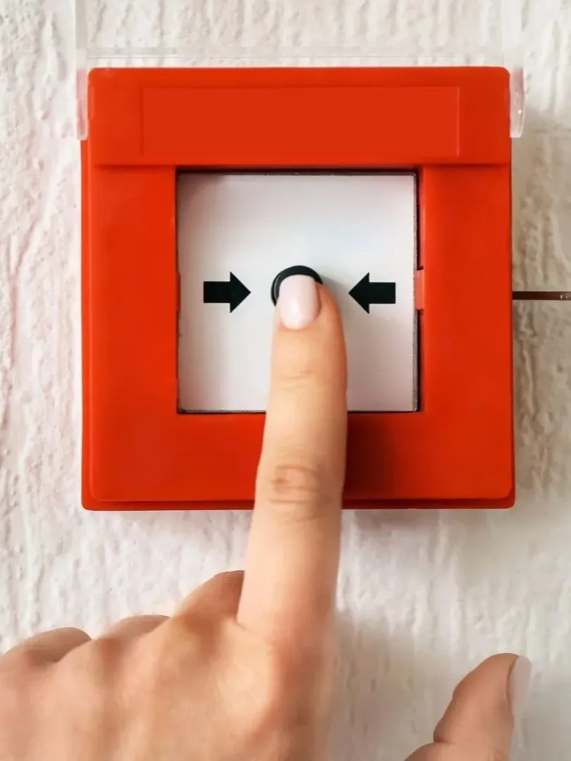 eine Frau drückt mit Ihrem Finger auf die Brandmeldeanlage