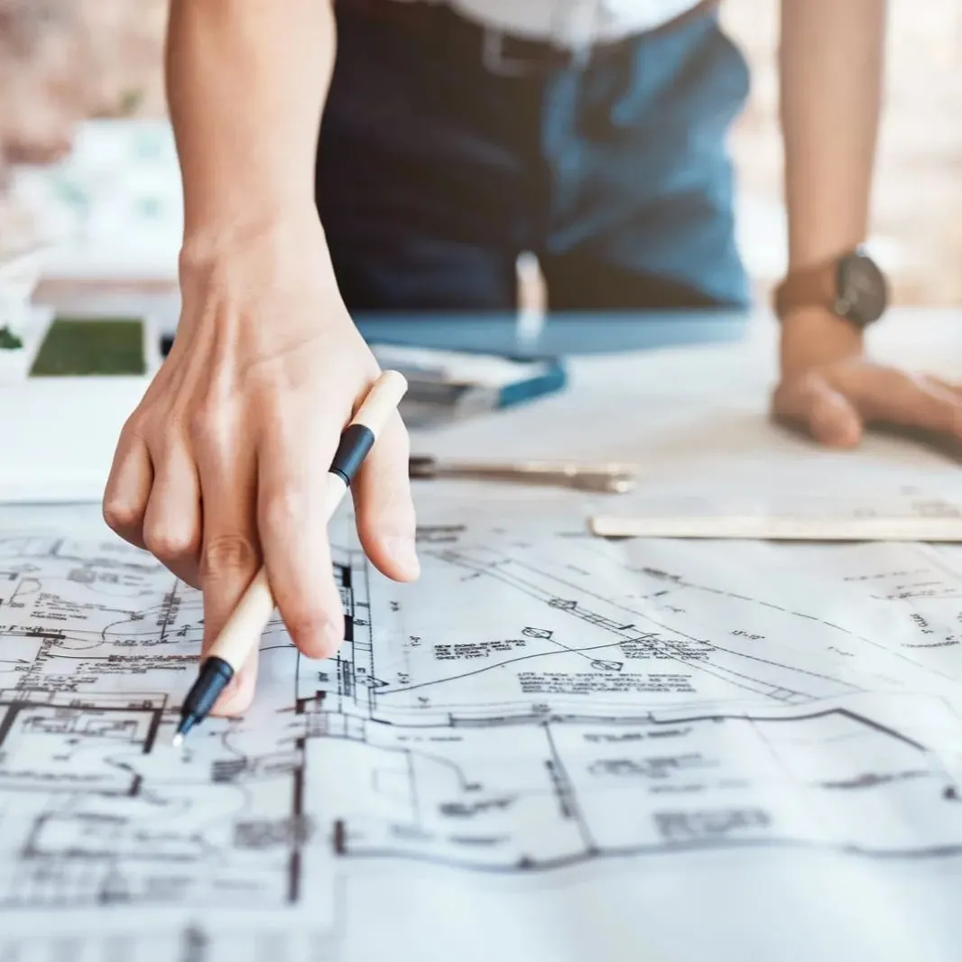 Ein Projektplaner oder Ingenieur deutet mit seiner Hand auf ein Detail des Bauplans.