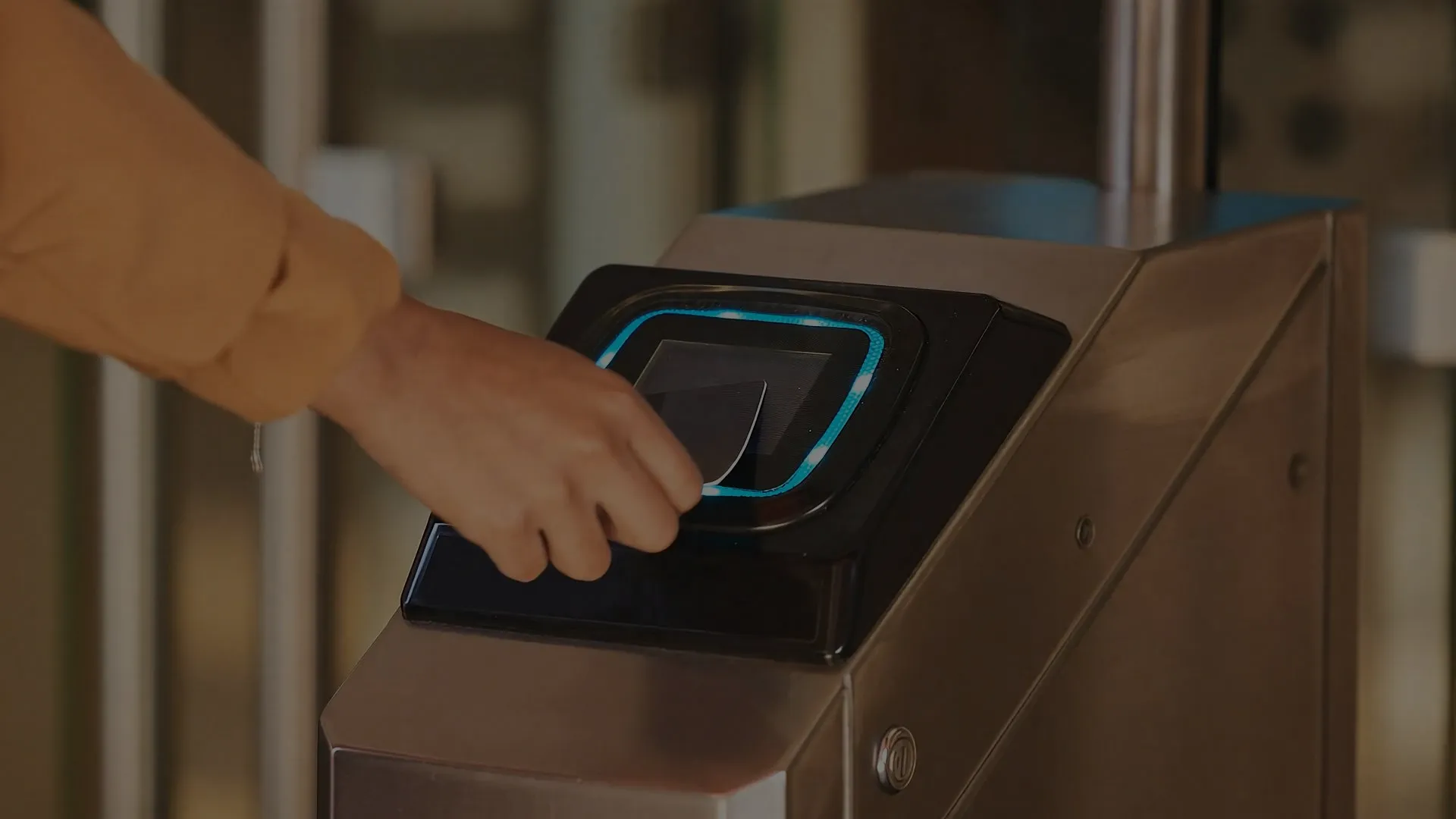 Eine Hand drückt eine Zugangskarte auf das Lesegeräte des Scanners der Zugangskontrolle