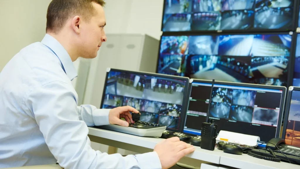 IT-Techniker überpfrüft die Videoüberwachungsanlage auf mehreren Bildschirmen und Laptops