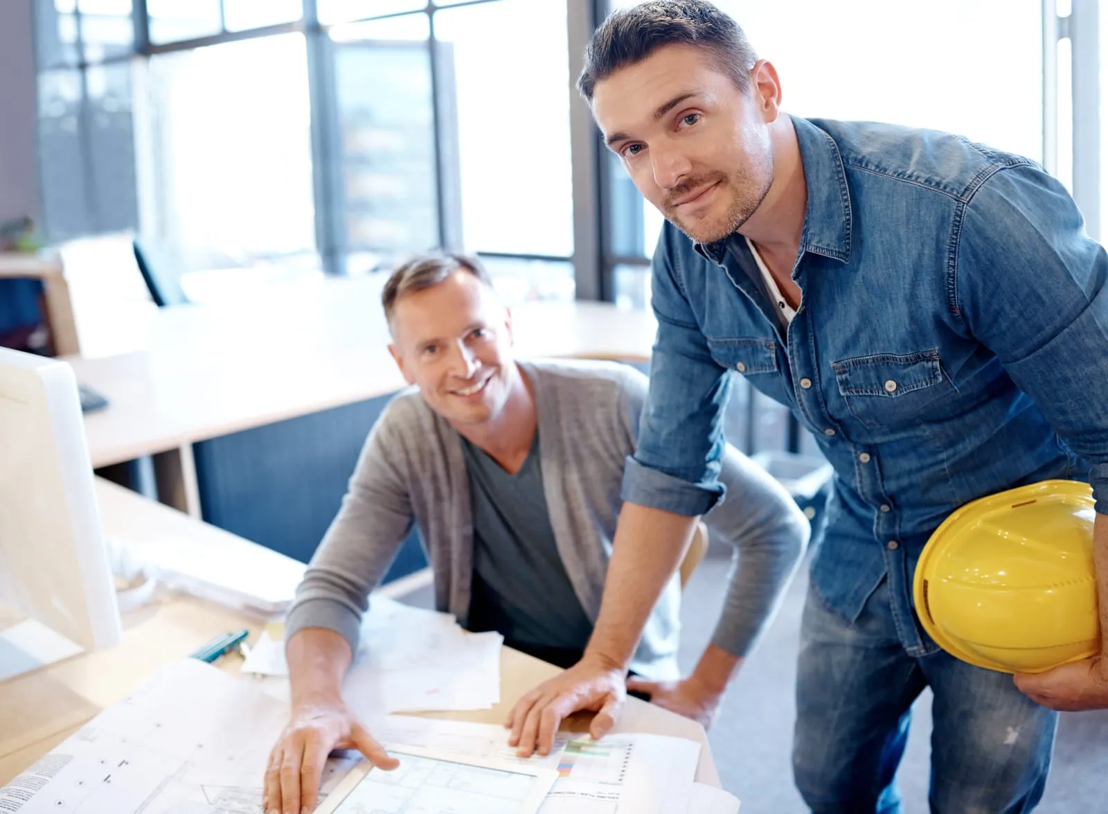 Sparolin-Elektrotechnik-2 Männer lächeln in die Kamera während sie einen Plan besprechen