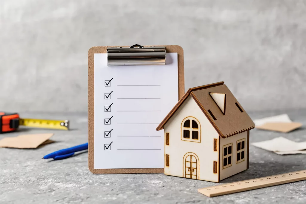 Ein kleines Holzhaus steht neben einer Checkliste.