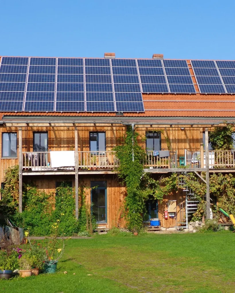Mehrfamilienhaus mit Photovoltaikmodulen und grünem Garten
