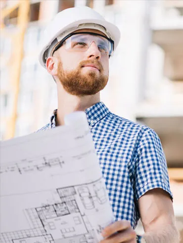 Sparolin-Elektrotechnik-junger Mann - Architekt auf der Baustelle - ein junger Architekt blickt von seinem Bauplan über die Baustelle.